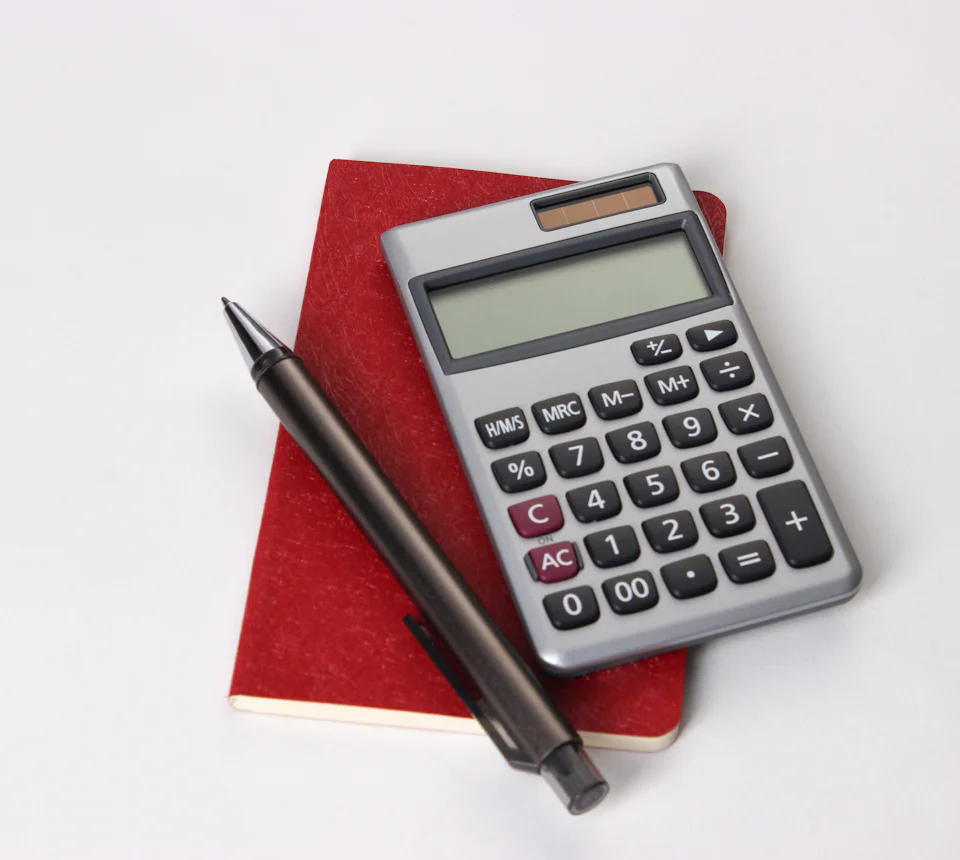 Calculadora e caneta sobre um caderno