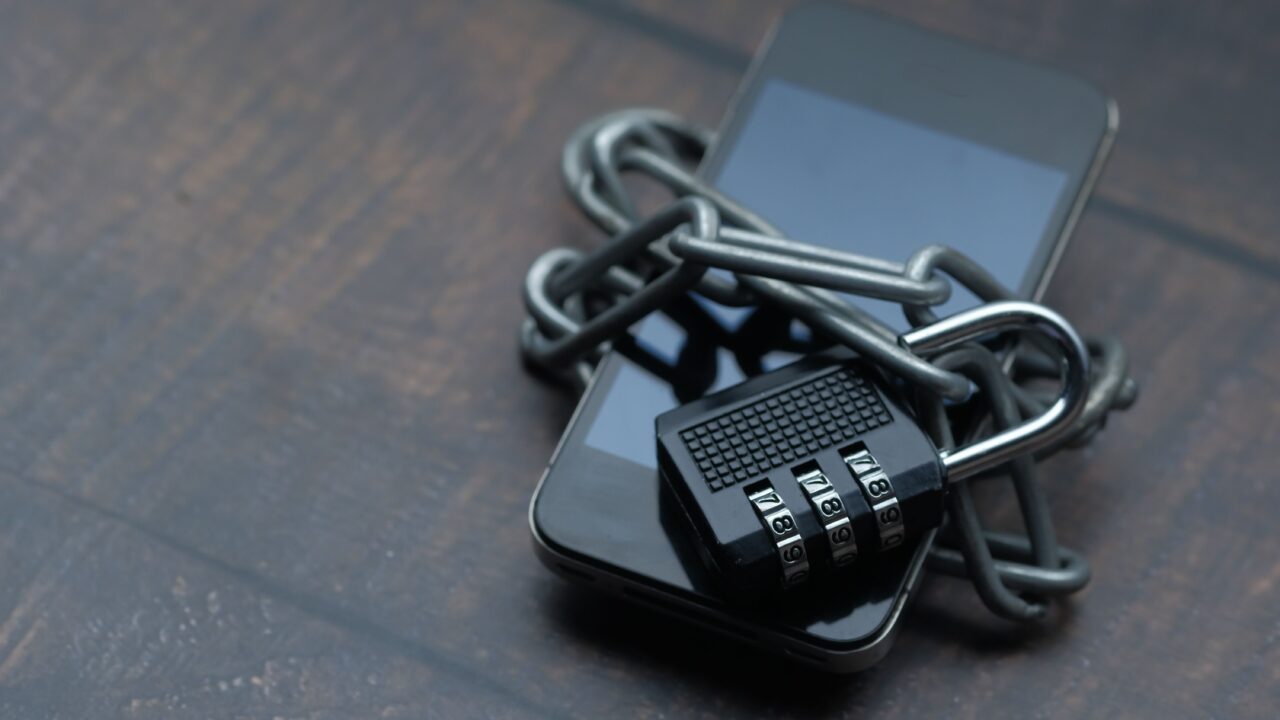 Celular preso por uma corrente e cadeado, representando a proteção de dados após um CPF vazado na internet