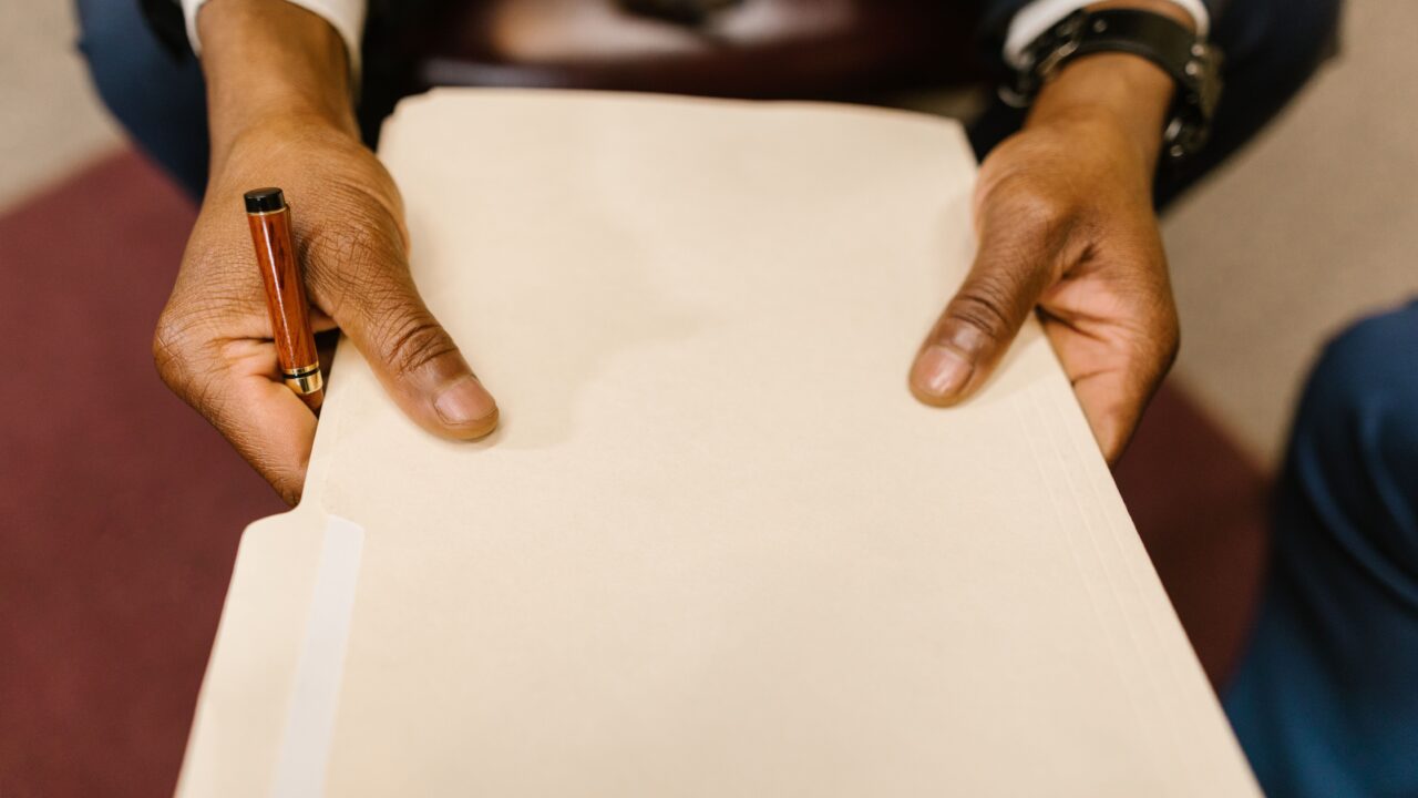 Mãos segurando uma pasta de documentos, representando a consulta de processos judiciais de uma empresa por CNPJ