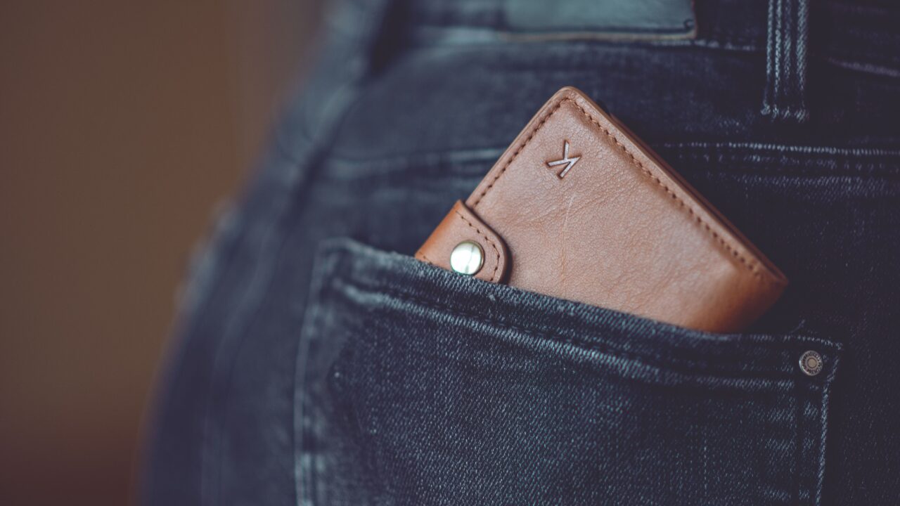 Close de uma carteira de couro marrom guardada no bolso traseiro de uma calça jeans