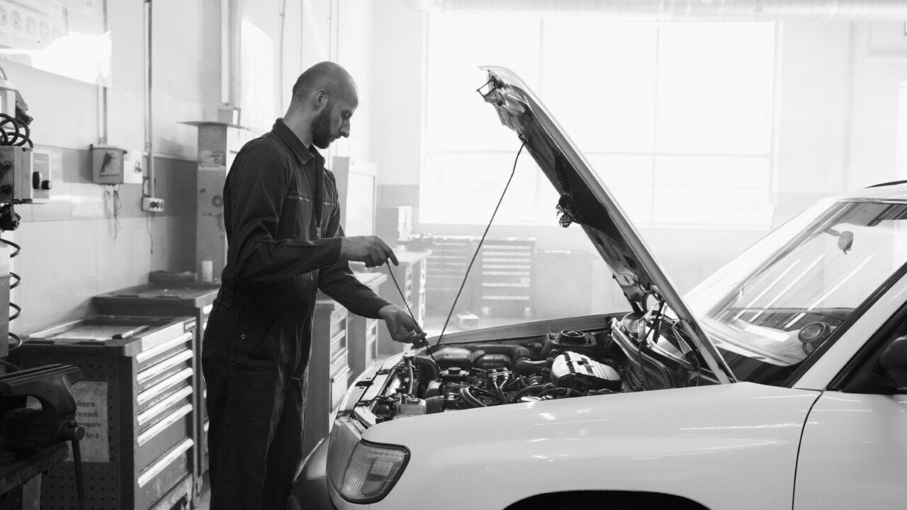 Mecânico examinando o motor de um carro durante vistoria veicular