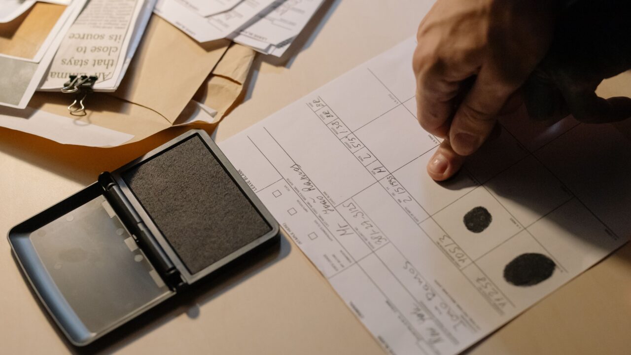Mão carimbando documento de identificação, ilustrando verificação de fraude cadastral