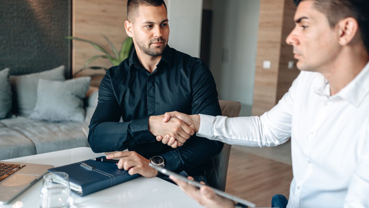 Dois empresários apertando as mãos em reunião de negócios