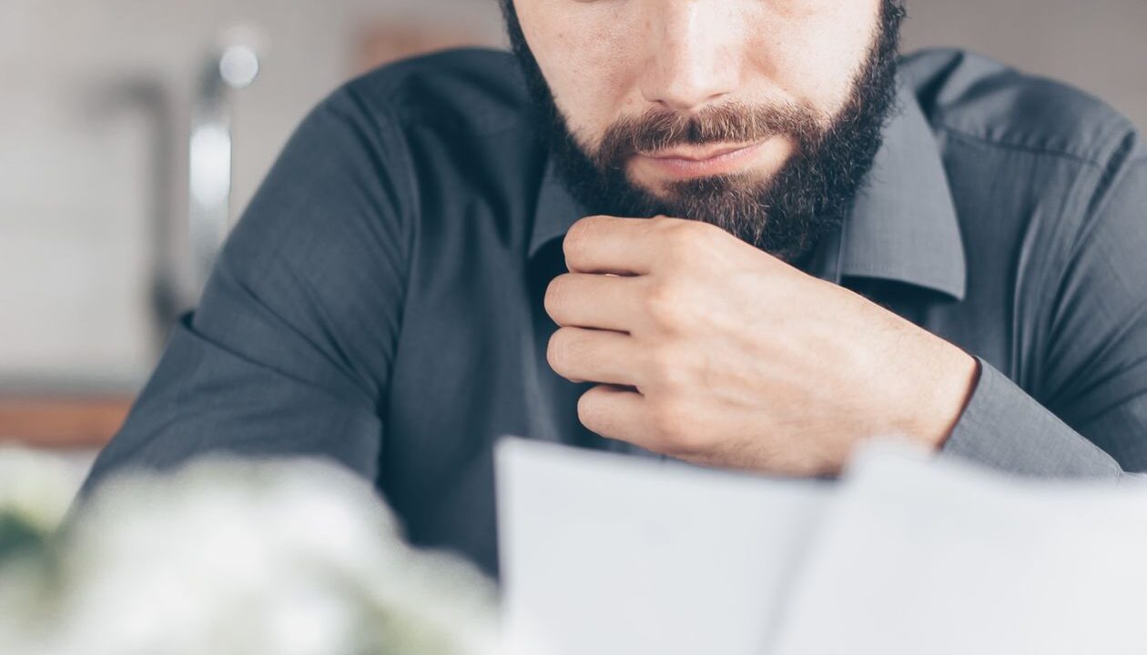 Homem com expressão preocupada lendo um documento em papel