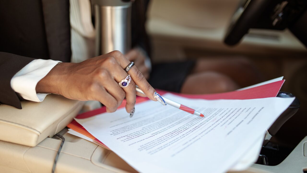 Mão assinando documento de licenciamento de veículo dentro do carro