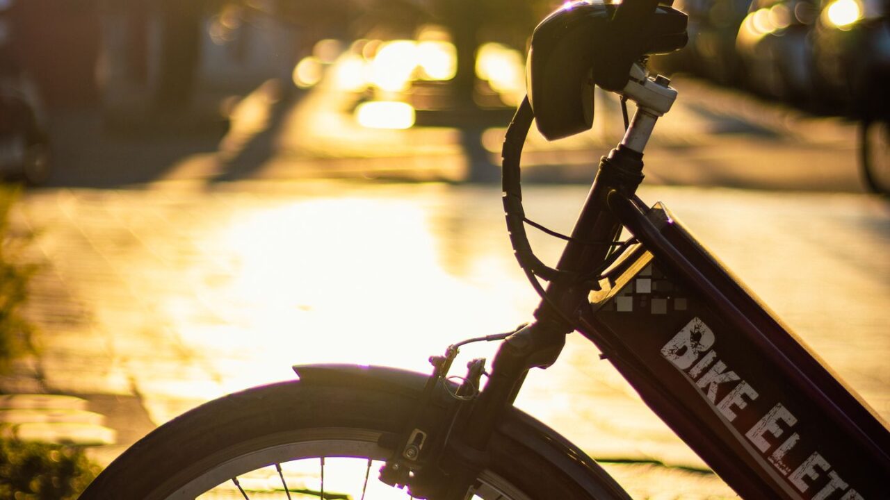 Silhueta de bicicleta elétrica em rua urbana ao pôr do sol
