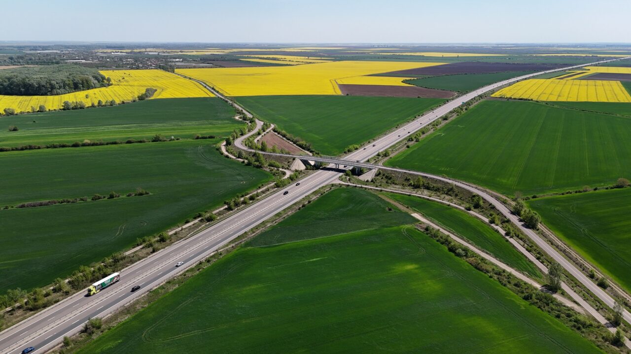 Vista aérea de rodovia cruzando campos agrícolas, simbolizando a mudança de estado com o veículo